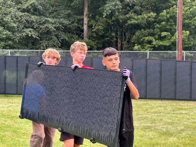 Young volunteers carry an inscribed panel between them