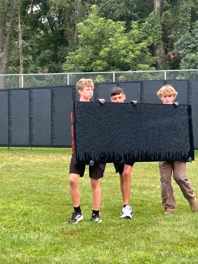 Student volunteers lift a panel into place along the Wall