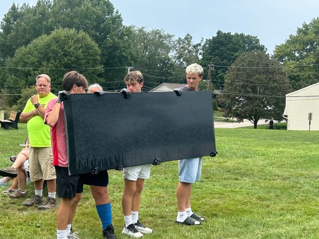 Volunteers steady a panel of names as they carry it