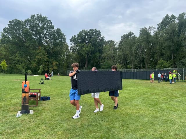 Volunteers carry a panel across the park as the Wall rises behind them