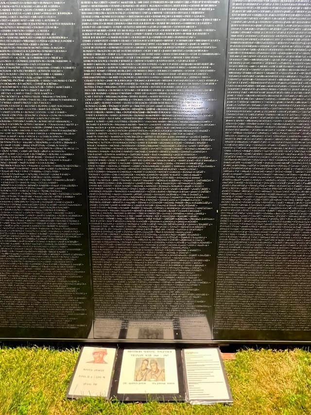 Panels of names lit at night, with the name directory at the base