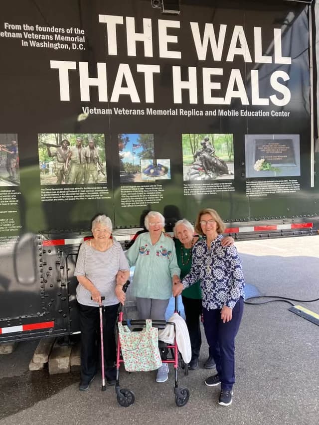 Four visitors together in front of the Mobile Education Center