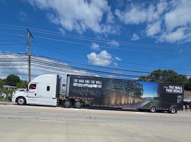 The exhibit trailer parked along the road under a blue sky