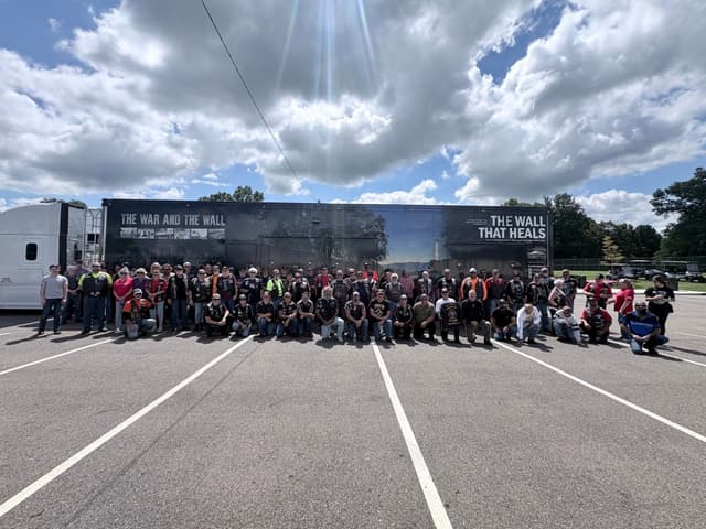 Escort riders posed in front of the trailer beneath heavy clouds