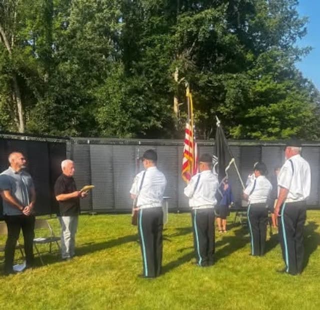 A color guard stands with flags beside the Wall