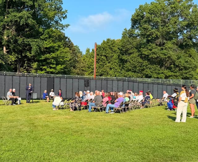 Neighbors seated on the grass for a ceremony at the Wall