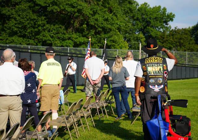Veterans and volunteers stand at the edge of a ceremony