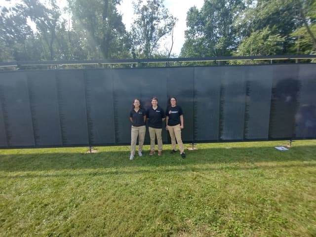 Three volunteers in front of the Wall